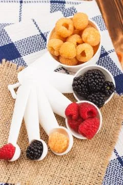 Measuring spoons with different berries inside Foto stock