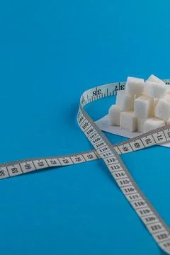Measuring sugar cubes on a blue background with a ruler present Stock Photos