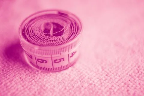 Measuring tape in box on the table. Pink tone. 스톡 사진