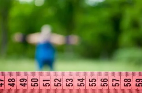 Measuring tape close-up, background on which a fat girl is warming up Stock Photos