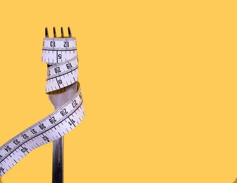 Measuring tape wrapped around fork on a yellow background, concept of diet .. Stock Photos