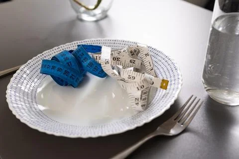 Measuring Tapes Positioned on a Plate, Serving as Reflections of Lifestyle and Stock Photos