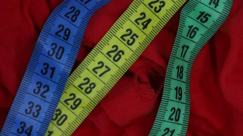 Measuring tapes on red fabric background  with light effect Stock Footage 185541033