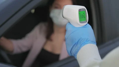 Measuring temperature of a driver with contactless thermometer, COVID-19 Stock Footage 156421354
