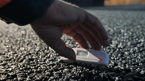 Measuring the temperature of fresh asphalt. Close-up of a man's hand adjusts the Stock Footage 137971465