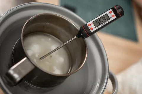 Measuring temperature of melted wax while making homemade candles. Stock Photos