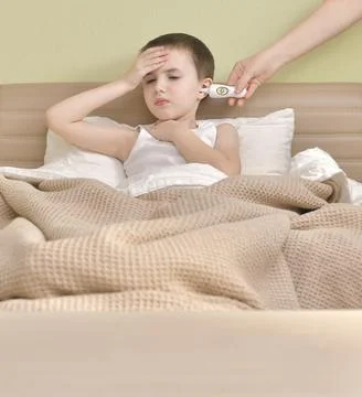 Measuring the temperature of a sick child in bed. Stock Photos
