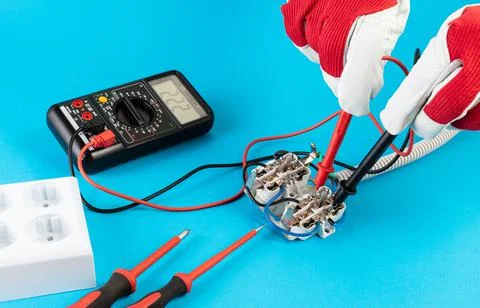 Measuring voltage with a multimeter at the contacts of an electrical outlet Stock Photos