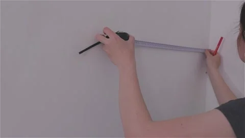 Measuring the wall surface with a tape measure. A young woman renovating a room. Stock Footage 331959391