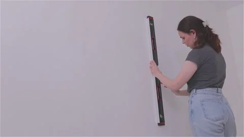 Measuring the wall surface with a tape measure. A young woman renovating a room Видео 332018973