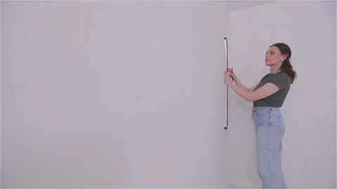Measuring the wall surface with a tape measure. A young woman renovating a room. Stockbeeldmateriaal 333122704