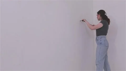 Measuring the wall surface with a tape measure. A young woman renovating a room Video stock 333582183