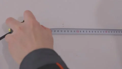 Measuring the wall surface with a tape measure. A young man renovating a room. Video stock 335619674