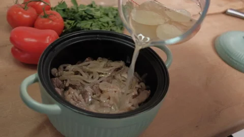 Meat and onions in a baking pan are poured with broth. Traditional cuisine Stock Footage 262434937