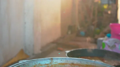 Meat and vegetable soup is cooked in a large cast-iron cauldron over an open Stock Footage 156411770