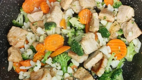 Meat and vegetables are fried in a frying pan Vidéo 168912441