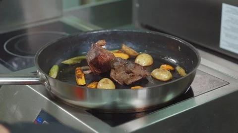 Meat and vegetables are roasting in frying pan on cooker, close-up Stock Footage 102978322