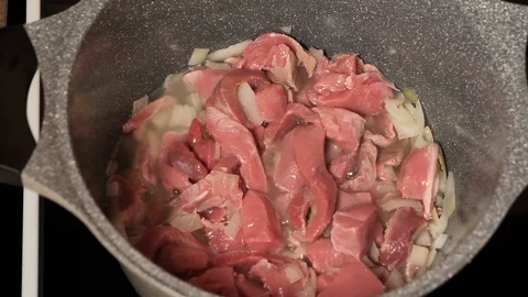 Meat beef cut into small pieces fried in a pan with smoke, close-up Stock Footage 128057082