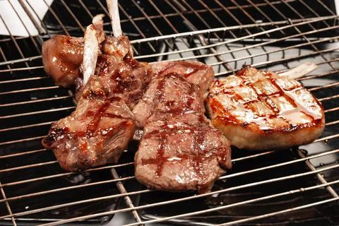Meat with a bone cooked on the grill with a grill rack Stock Photos