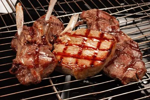 Meat with a bone cooked on the grill with a grill rack Stock Photos