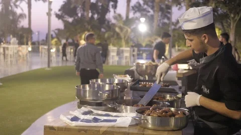 Meat Buffet Waiter Preparing his Hotdogs and Burgers To Be Served Stock Footage