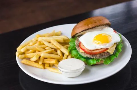 Meat Burger with egg, sauce and fries Stock Photos