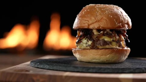 Meat cheeseburger with caramelized onion on black plate slide onto the frame Видео 170319024
