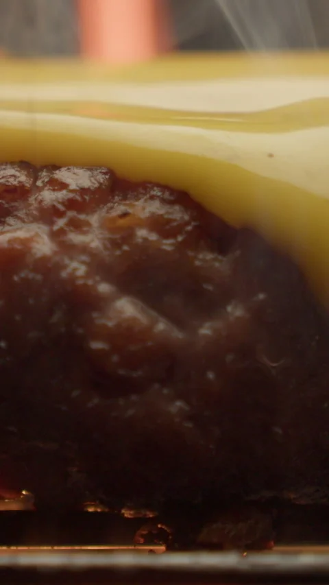 A meat cutlet with cheese flowing over is cooked on a fire vertical video 스톡 동영상 310955745