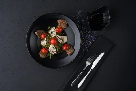 A meat dish on a black surface Stock Photos