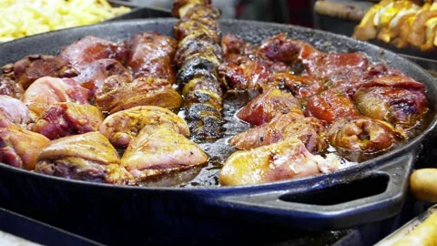 Meat dishes are cooked in a large frying pan at a street cafe Christmas market Stock Footage 224148106
