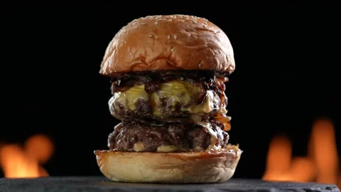Meat double cheeseburger on black plate turntable on flaming background. Video stock 170319953