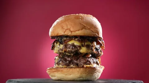 Meat double cheeseburger with caramelized onion on turntable on red background. Stock Footage 170320027
