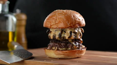 Meat double cheeseburger with top burger bun falling on top on a wooden table. Stock Footage 170319567
