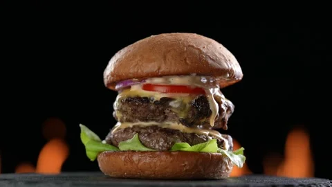 Meat double cheeseburger with vegetables on black plate on flaming background. Stock Footage 170319432