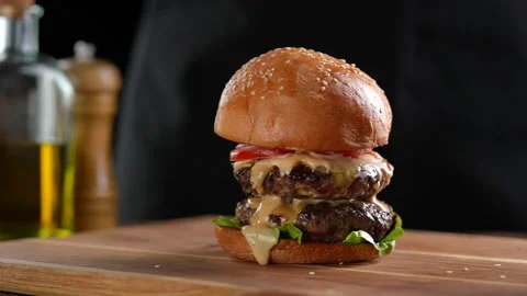 Meat double cheeseburger with vegetables with top burger bun falling on top. Stock Footage 170319930