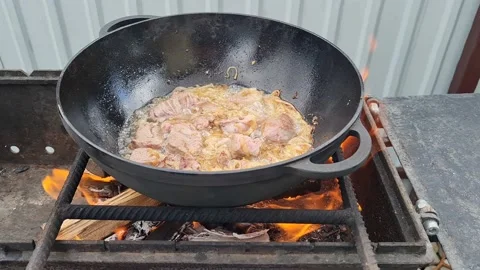 Meat is fried in a cauldron over an open fire. pilaf preparation process Stock Footage 152632999