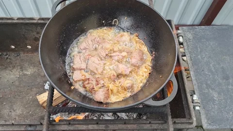 Meat is fried in a cauldron over an open fire. pilaf preparation process Stock Footage 152633061