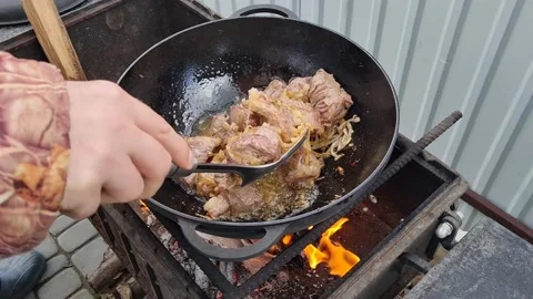 Meat is fried in a cauldron over an open fire. pilaf preparation process Stock Footage 152633135
