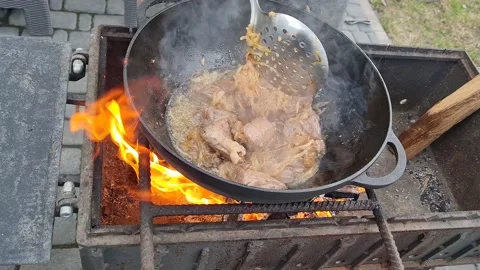 Meat is fried in a cauldron over an open fire. pilaf preparation process Stock Footage 152633303