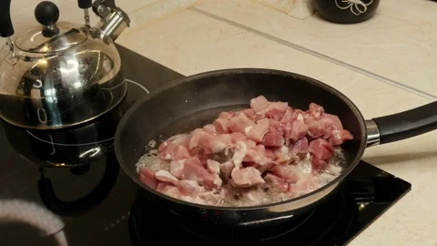 Meat frying in a pan on a black induction cooker Stock Footage 135933382