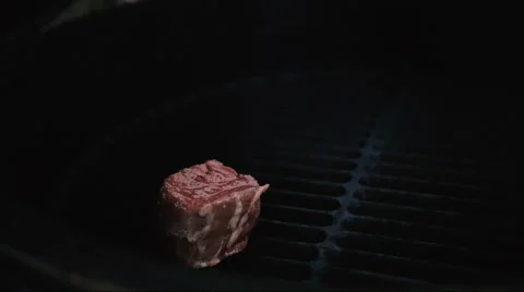 A meat on a gas grill with open flames is cooked with a metal spatula Video stock 67353980