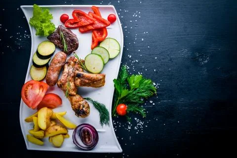 Meat grilled assorted and vegetable sliced. On a wooden background. Top view. Stock Photos