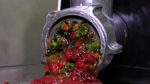 A meat grinder squeezes out green herbs and red tomatoes Stock Footage 341765427