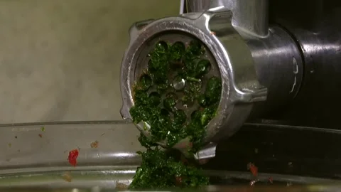 The meat grinder squeezes out green herbs and red tomatoes for fresh juice Stock Footage 341765576