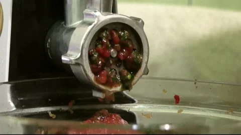 The meat grinder squeezes out healthy green herbs and red vegetables for fresh Stock Footage 341765458