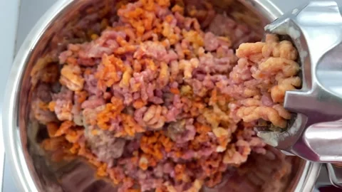Meat grinder twists fresh meat with carrots into metal bowl. Top view. Close up Stock Footage 160057067