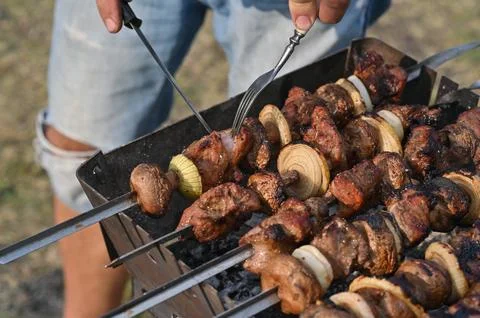 Meat kebab is cooked on the grill. checking the readiness of the barbecue. Stock Photos