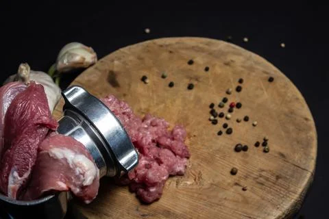 Meat in a meat grinder on a black background. Pork meat is twisted in an old mea Stock Photos