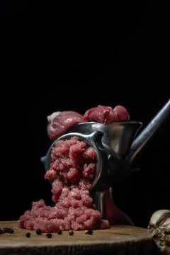 Meat in a meat grinder on a black background. Pork meat is twisted in an old mea Stock Photos