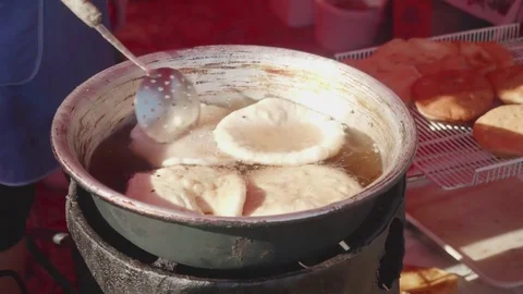 Meat pasty is being fried outside on open fire in a pot with oil Stock Footage 78478740